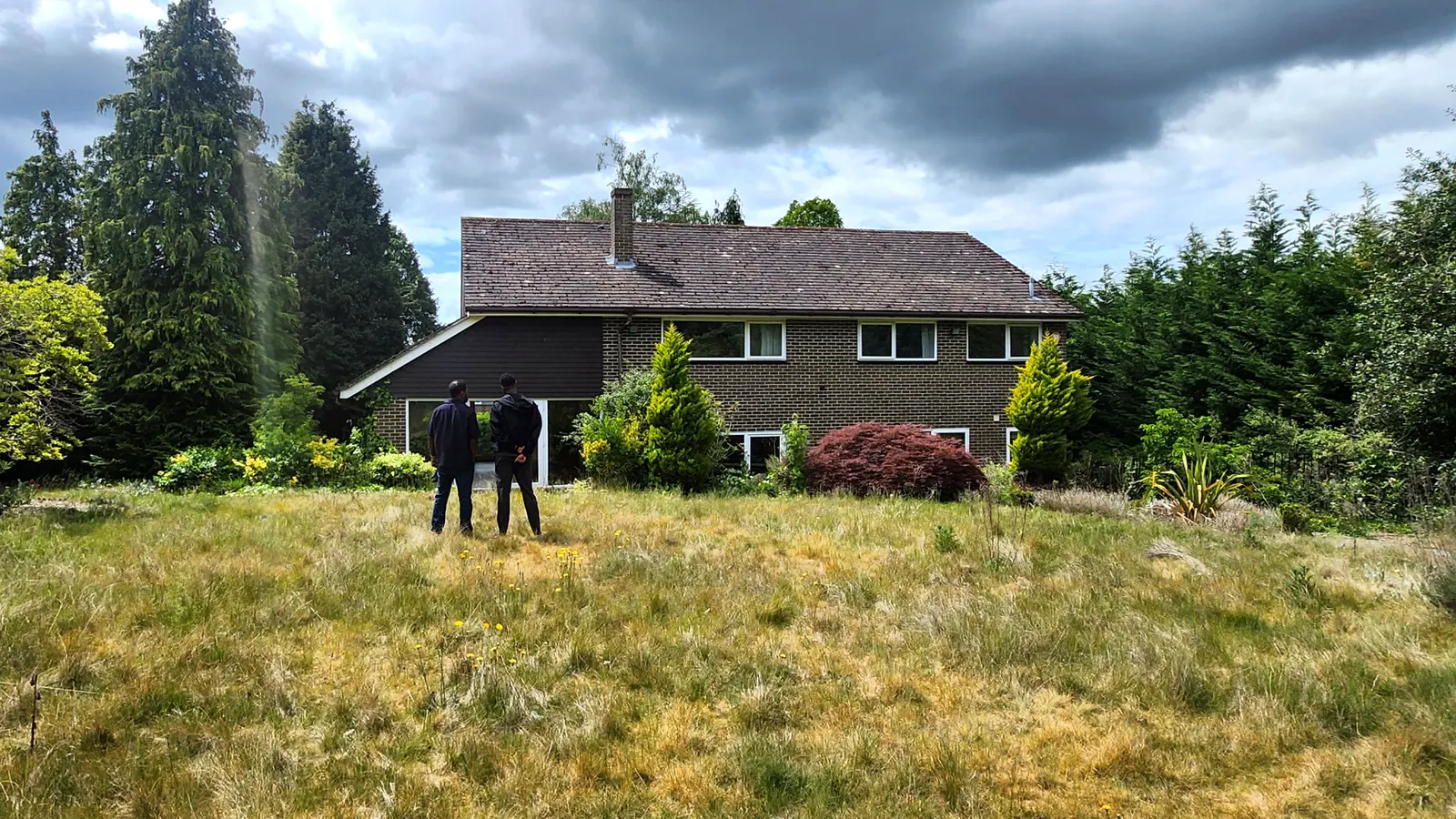 The Cobham house before the work, a dated brick house behind an overgrown garden