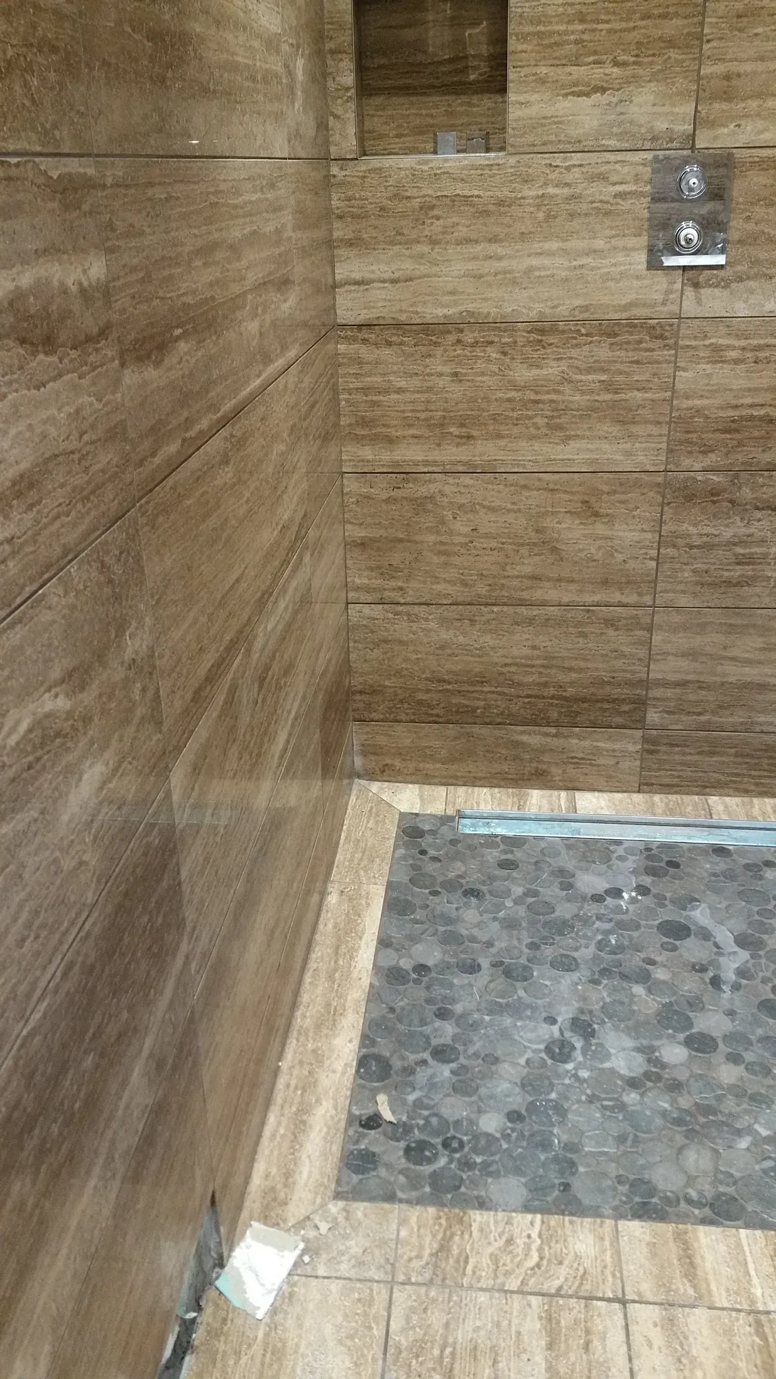 Travertine shower with a pebble floor