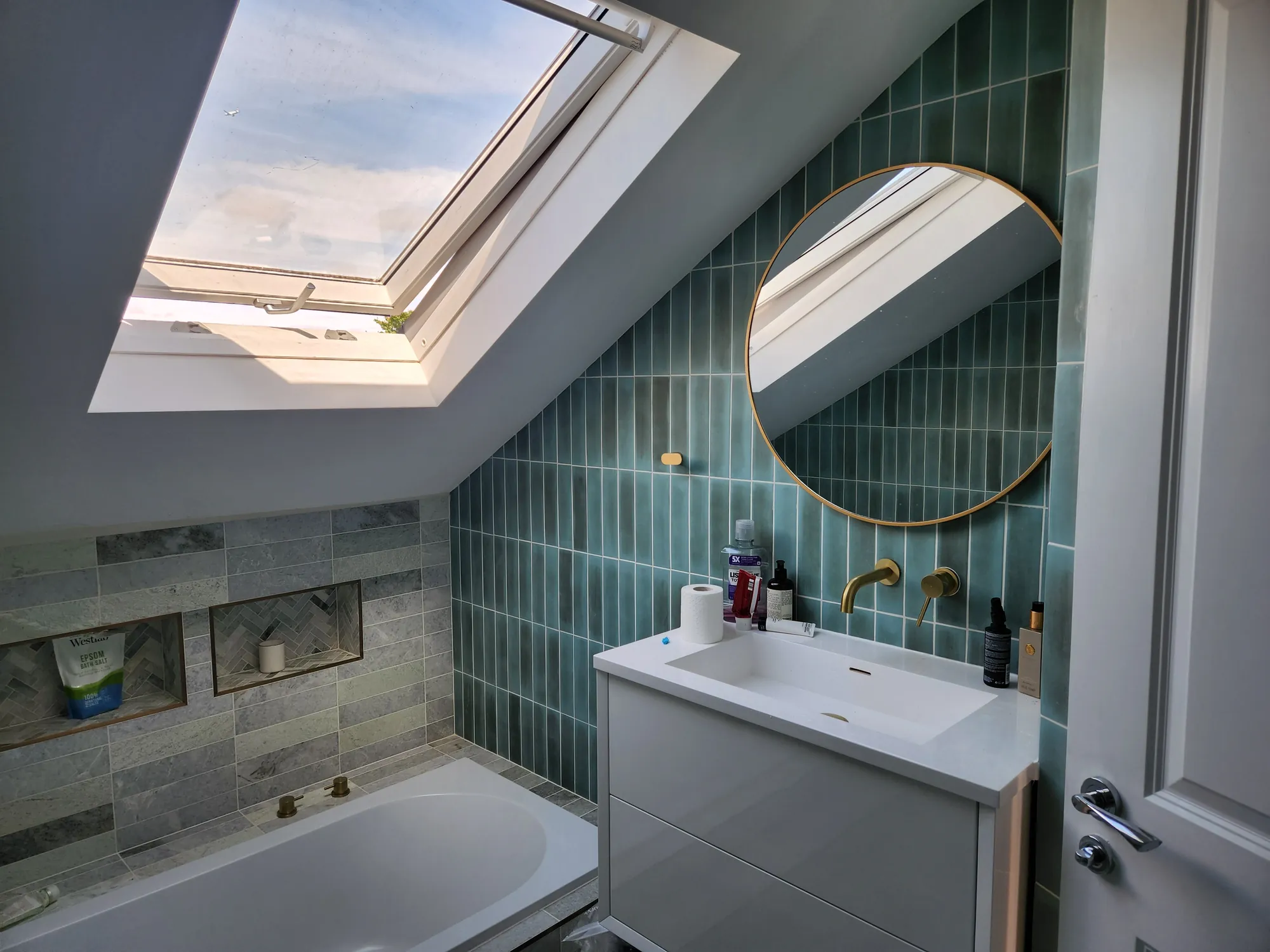 Loft bathroom with a round mirror and brass fittings
